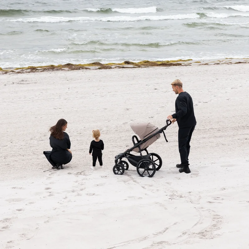 Familie am Strand mit dem Thule Urban Glide 4-Rad-Kinderwagen.