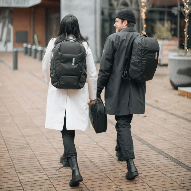 Zwei Personen gehen in der Stadt und tragen dabei Thule Accent Rucksäcke.