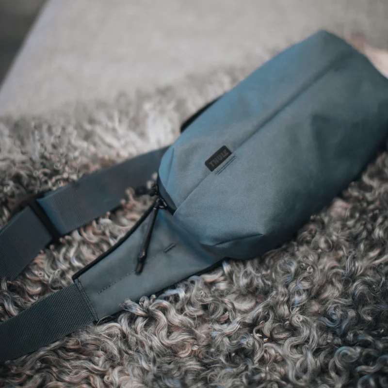 A close-up of the blue Thule Aion sling bag on a furry mat.