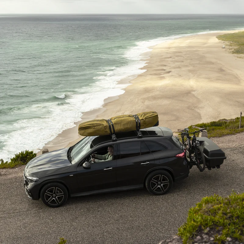 Auto ist am Meer geparkt mit einer Thule Aion Surfbretthülle auf dem Dach montiert