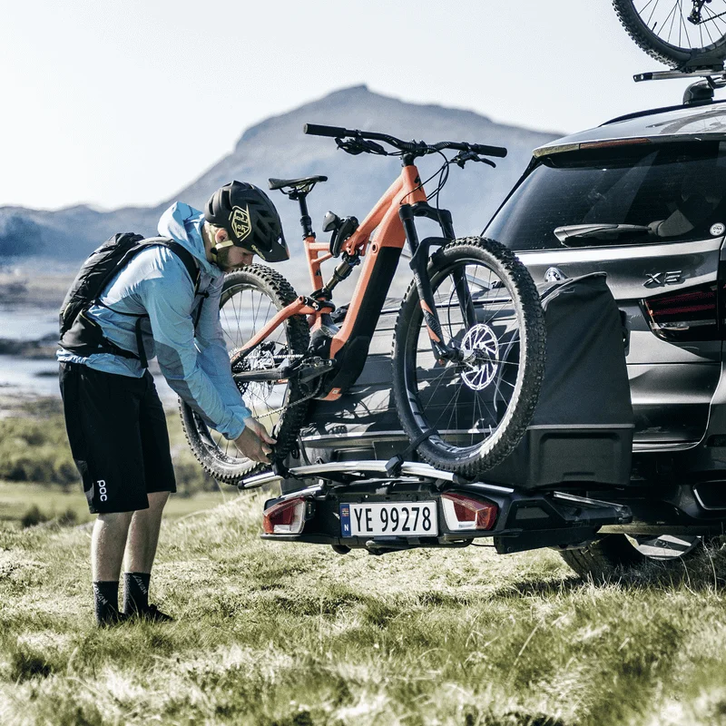 A cyclist loads the bike carrier with bikes using the Thule VeloSpace XT Bike Adapter..