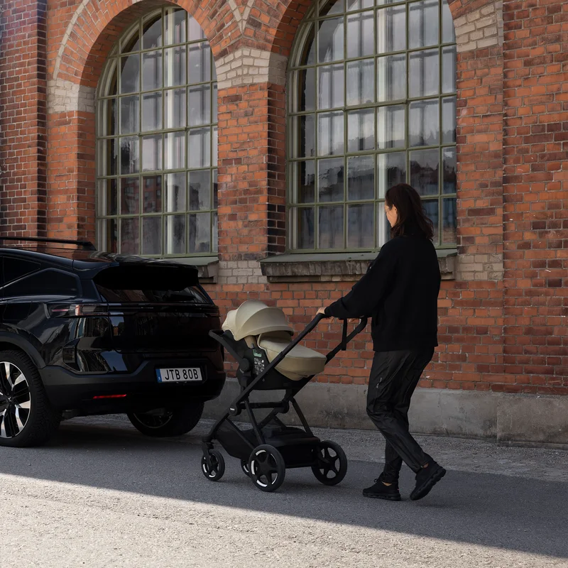 Adult pushing a Thule Charm stroller with an infant car seat attached using car seat adapters.