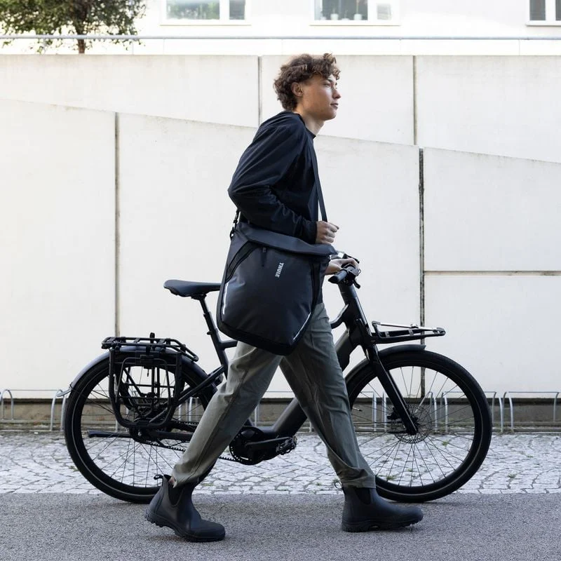 Pendler mit einer Thule Chasm Tasche neben einem Fahrrad.