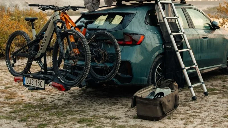 Thule Chasm Gepäcktasche 55L neben einem Auto mit Fahrrädern und Ausrüstung
