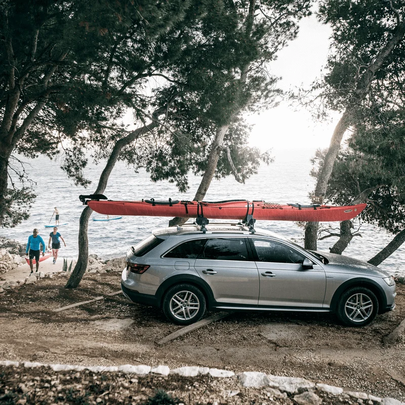 A car is parked by the sea with a kayak on the roof