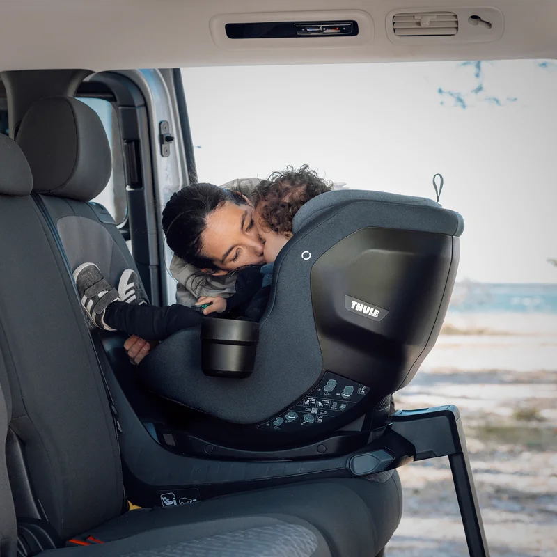 Adult attaching a Thule Elm Connect toddler seat to the Thule Alfi Connect ISOFIX base in the back seat of a vehicle.