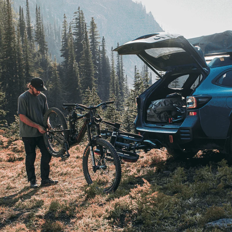 A man standing in the woods is repairing his bike using a Thule Epos Bike Repair Holder