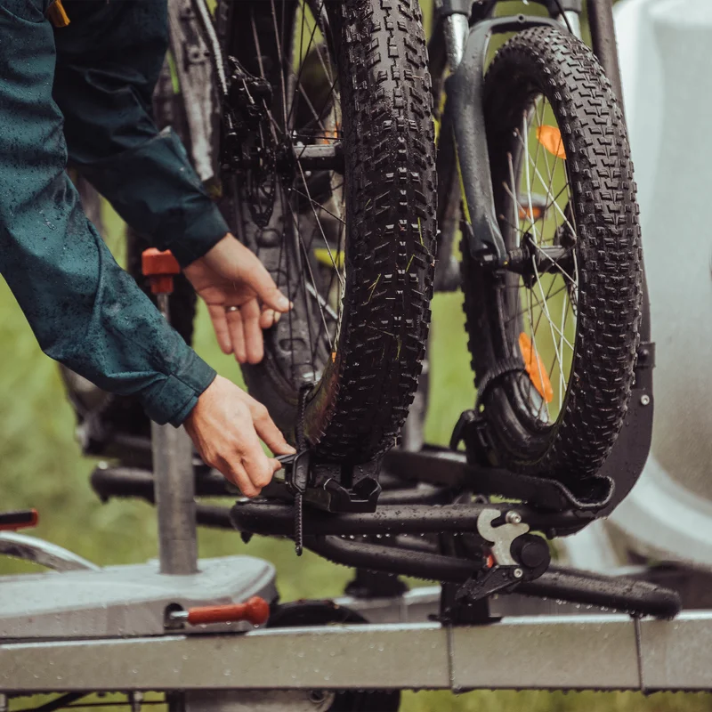 A person attaches a bike to a bike rack using a Thule Fatbike Rail Short Black.