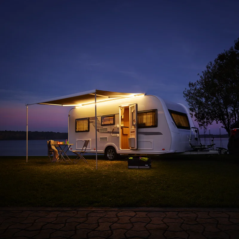 A white van overlooking the mountains and an awning with a Thule LED Strip van light.
