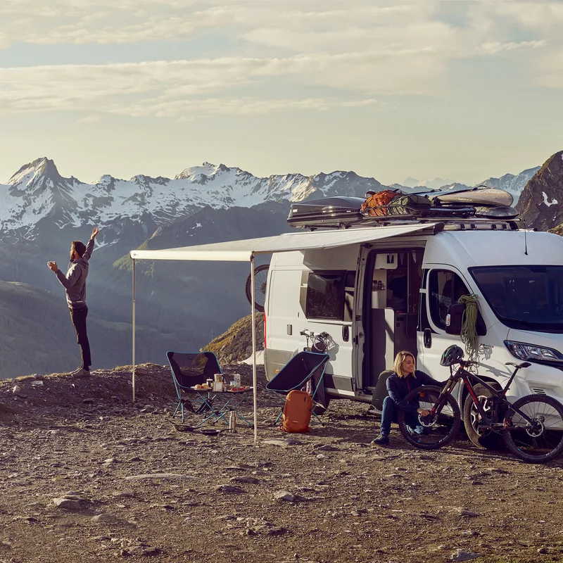 A person looking at mountains standing next to a motorhome with a Thule Omnistor 6300 van awning.