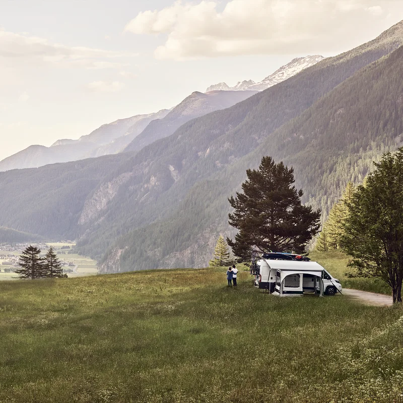 An rv parked in the mountains with a white Thule QuickFit DuJuBo rv awning tent.