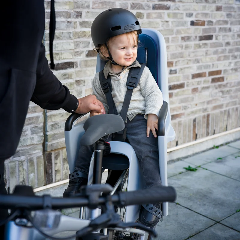 Nahaufnahme eines Kindes mit schwarzem Helm, das in einem Thule RideAlong2 Fahrradkindersitz sitzt.