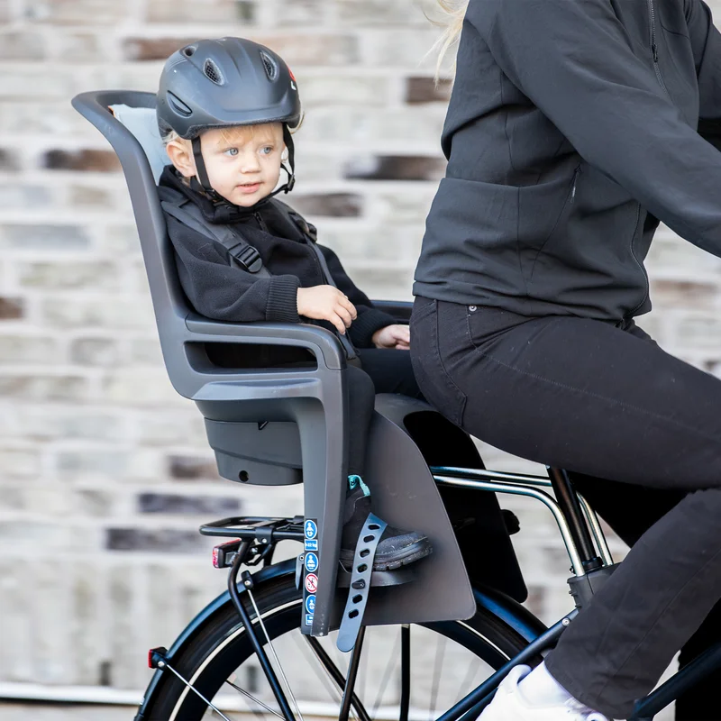 Ein Kind sitzt in einem Thule RideAlong2 Fahrradkindersitz, während die Eltern radeln.