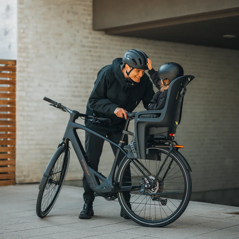 .Eltern sichern ihr Kind vor der Fahrt im Thule RideAlong 2 Fahrradsitz.