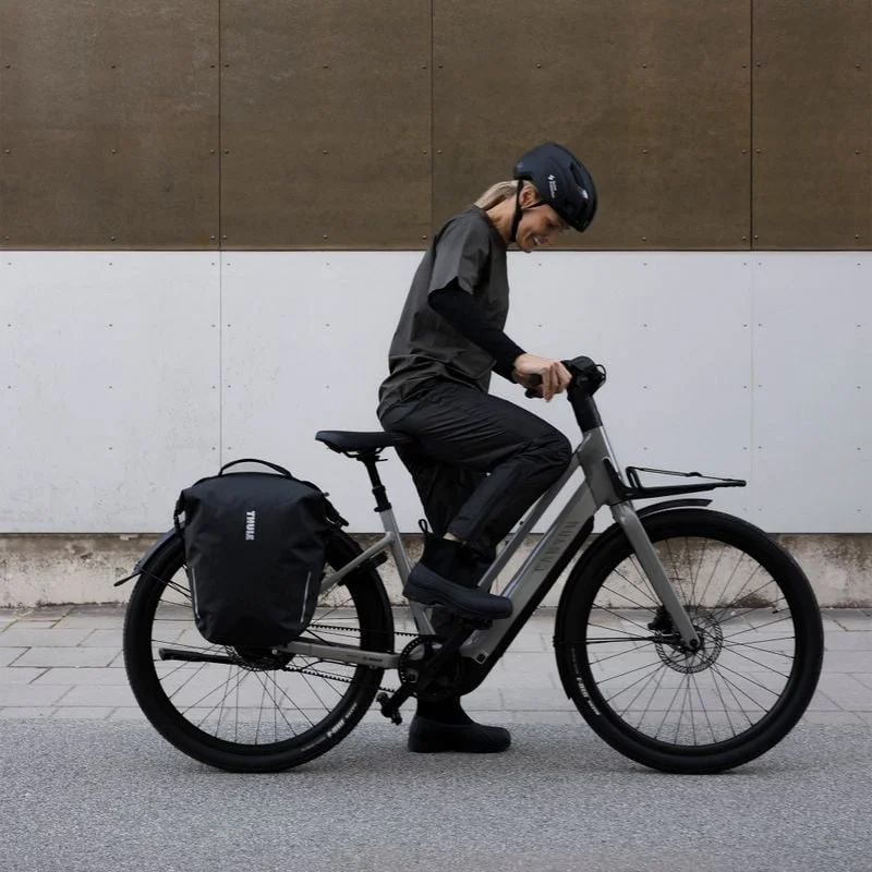 Radfahrer, der ein Fahrrad mit einer Thule Shield Tasche am hinteren Gepäckträger einstellt.
