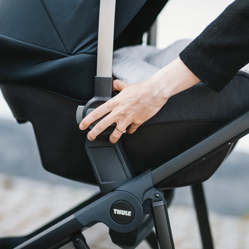 A close-up of a parent installing a car seat on the Thule Shine stroller using the Thule Shine Car Seat Adapter.