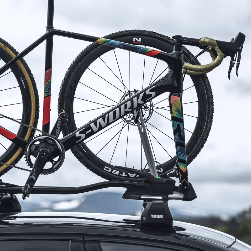 A road bike is mounted to a car with a Thule TopRide bike carrier
