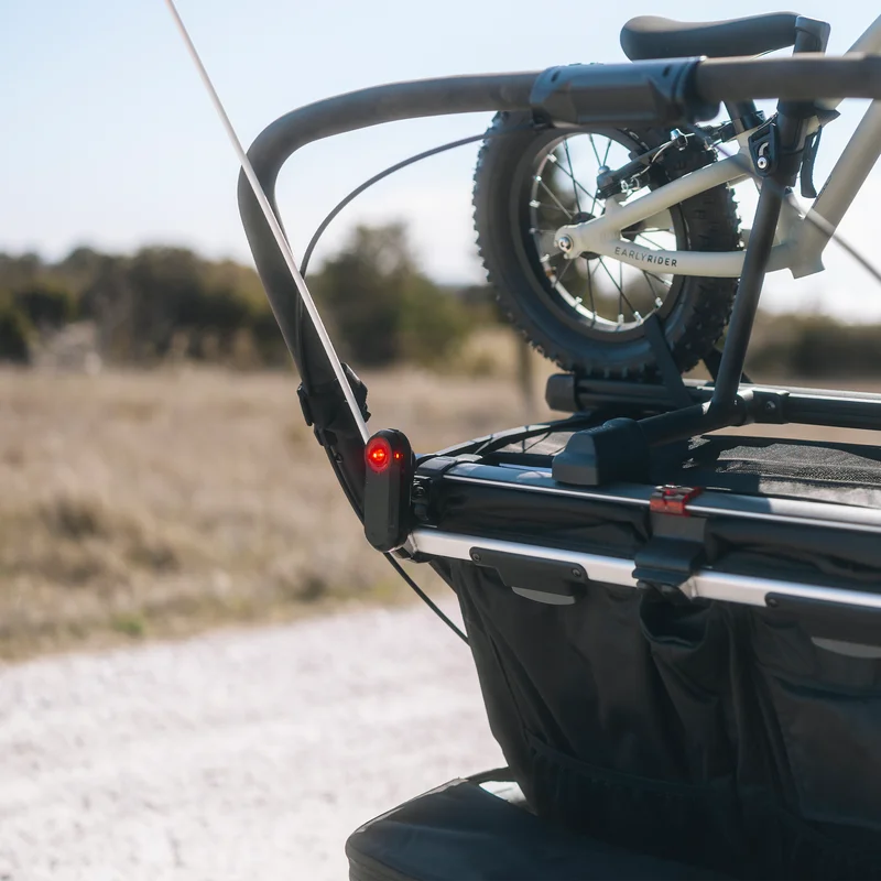 Thule handyhalterung für das Garmin Varia Rückfahrradar, befestigt an der Rückseite eines Fahrradanhängers, der ein Fahrrad transportiert.