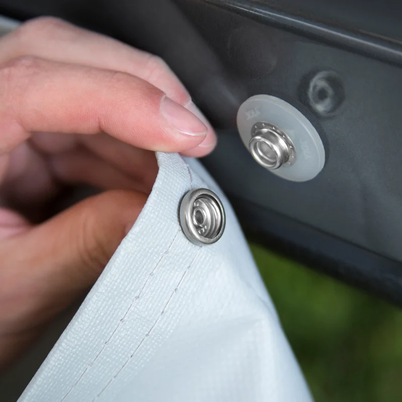 A close-up of someone placing a white Thule Wheelcover on an RV.